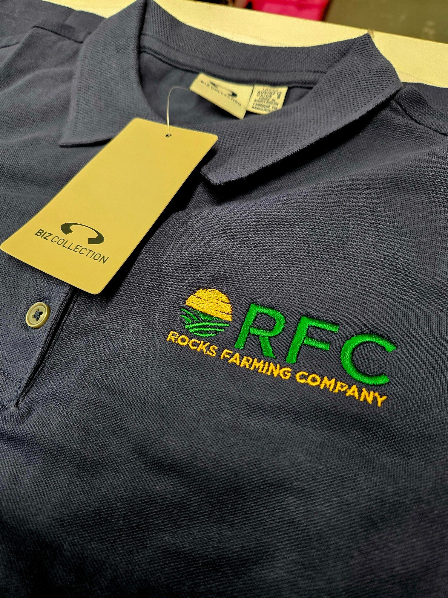 Navy blue polo shirt with embroidered RFC Rocks Farming
